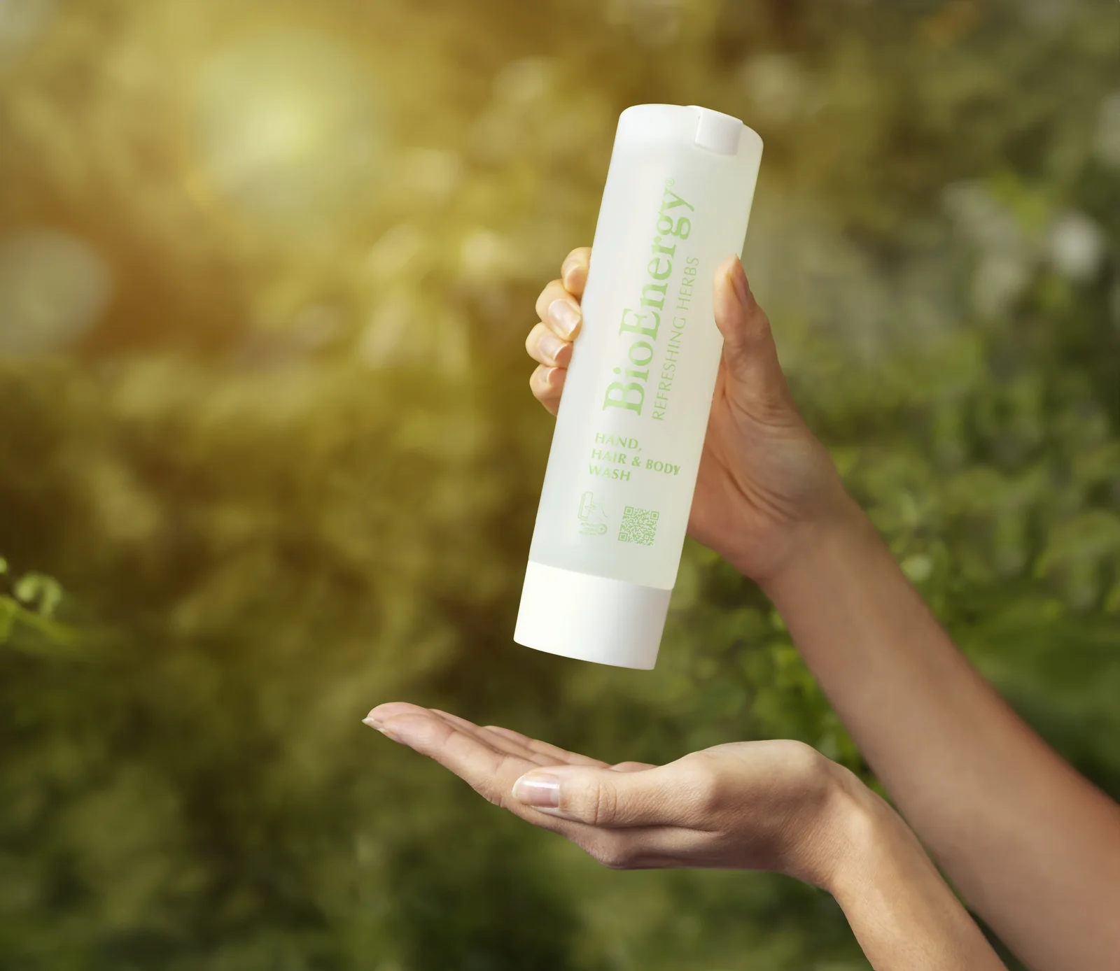 BioEnergy bottle held above a palm, against the green of a garden