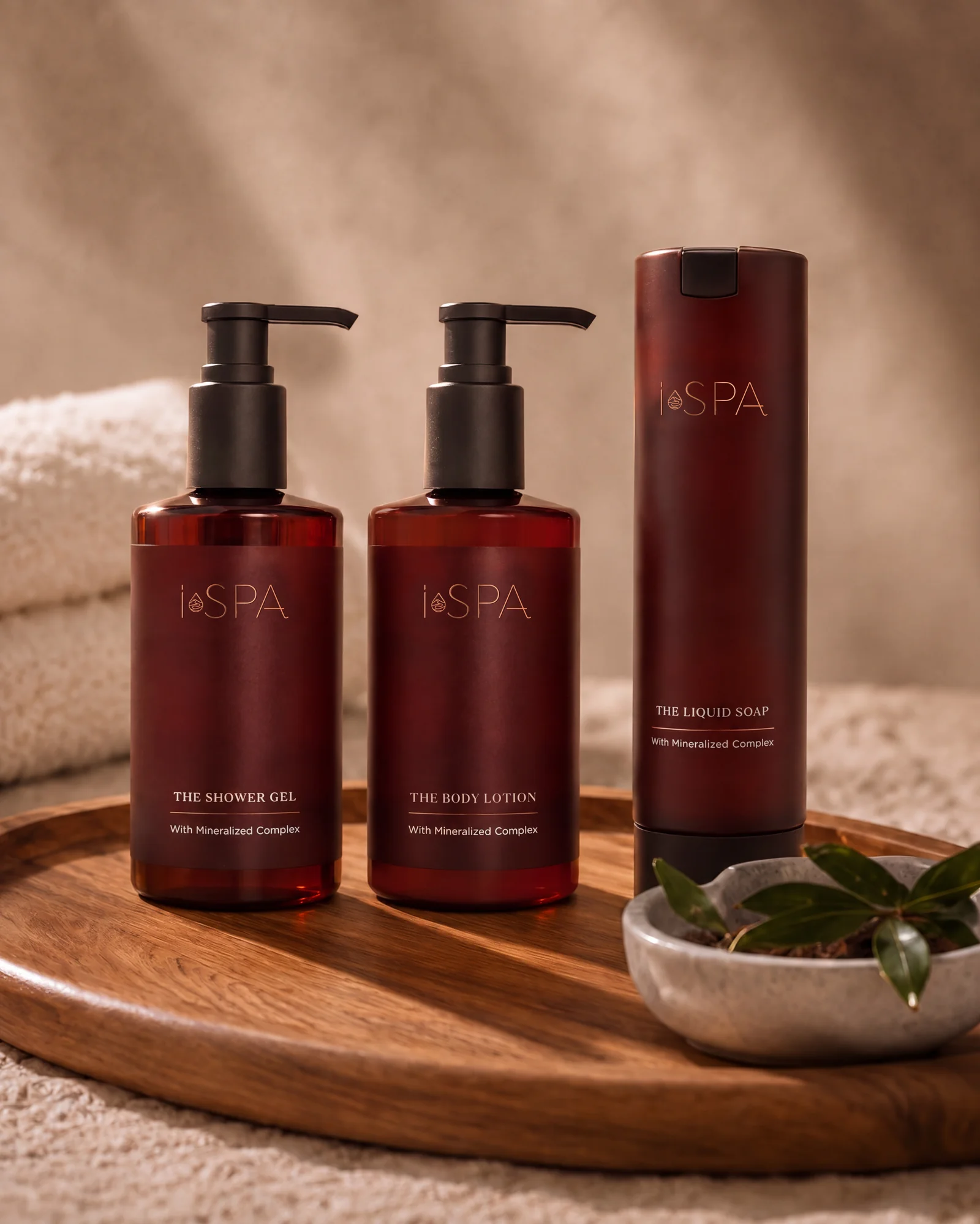 Three iSPA bottles on a wooden tray next to towels