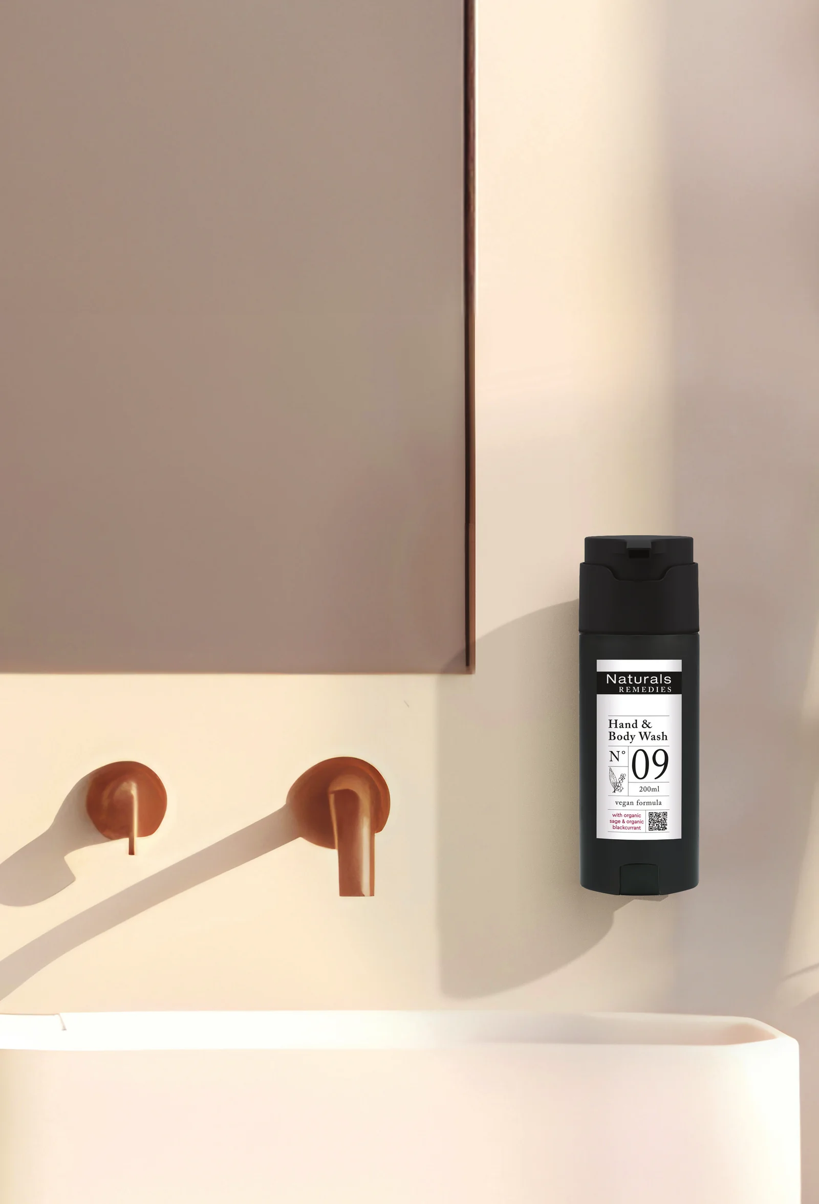 Dozator SHAPE MINI negru Naturals Remedies montat pe perete, deasupra lavoarului, lângă o baterie arămie