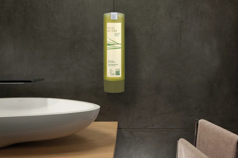 Dozator SmartCare Pure Herbs montat pe peretele de piatră al unei băi de hotel