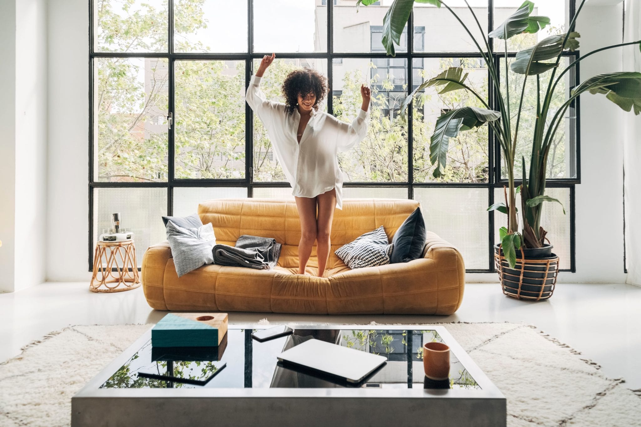 Woman dancing on a sofa in a bright living room, Be Different line visual