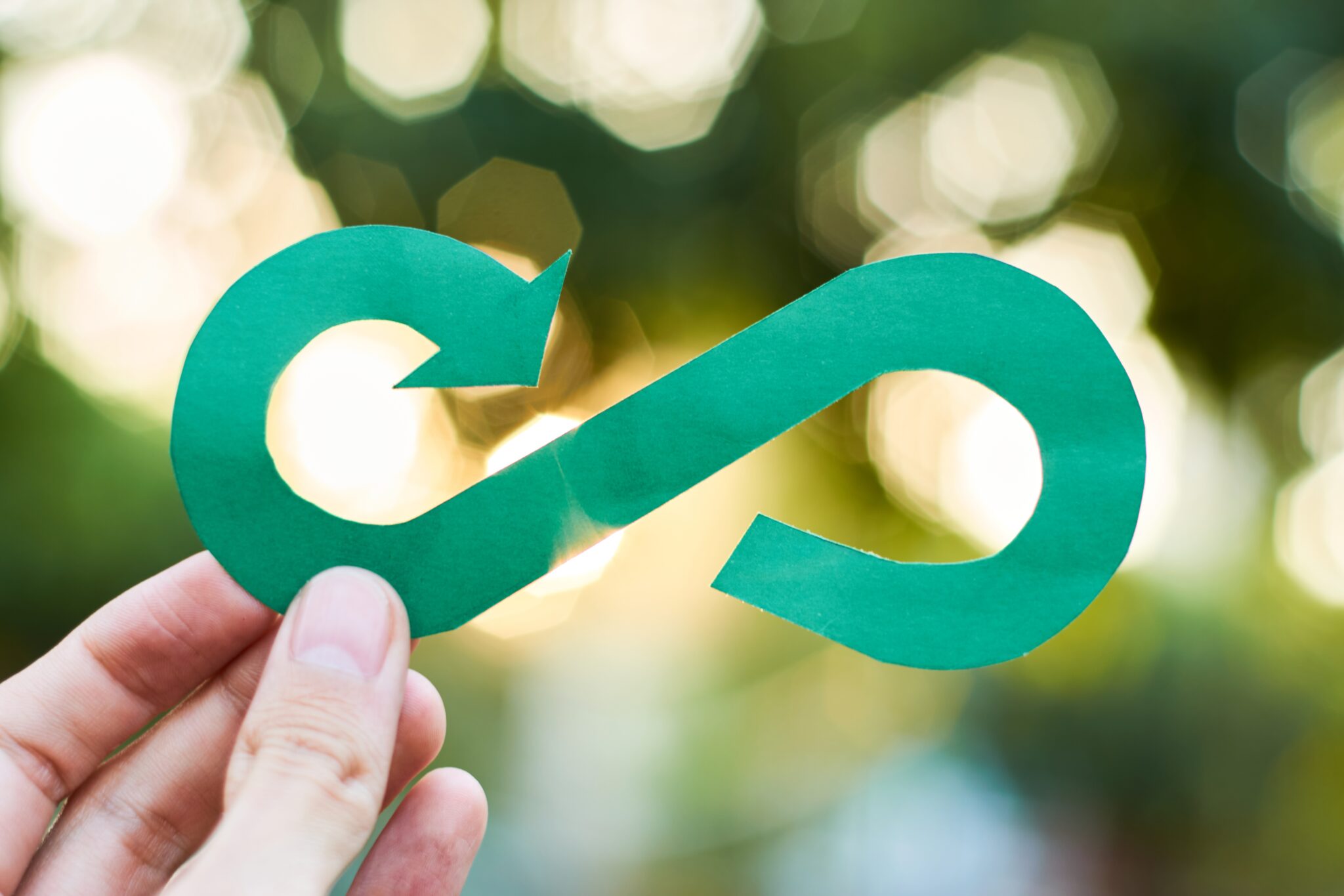 Hand holding a green paper circular economy symbol